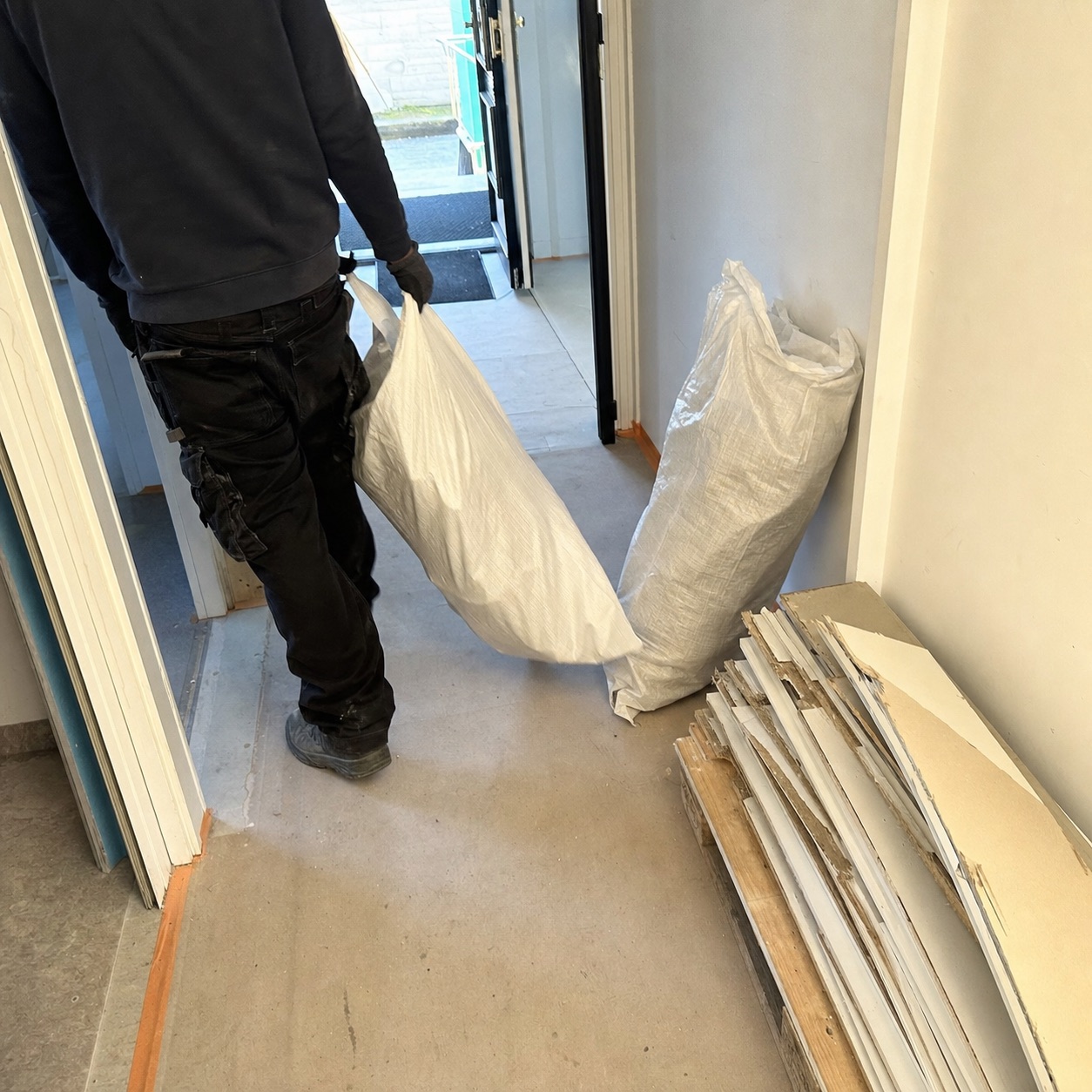Räumungsarbeit im Hausflur mit Bauschuttsack und demontierten Brettern